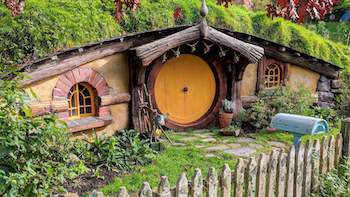 another pretty hobbit house with a yellow door and picket fence in the mountainside