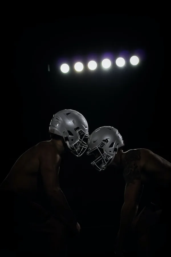 two football players in helmets under the stadium lights