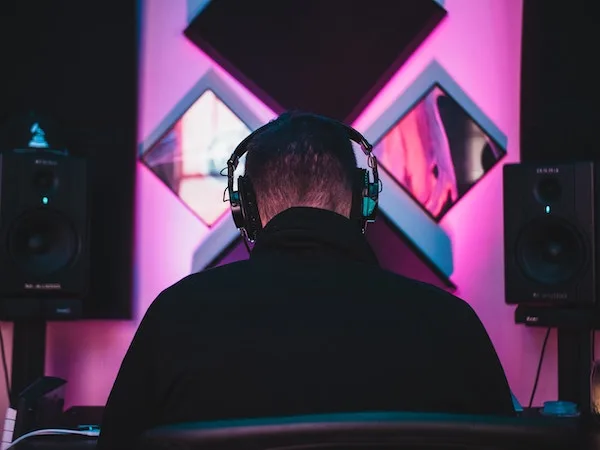 music producer sitting in front of a purple lit studio