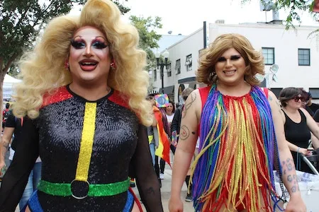 two drag queens walking down the street wth amazing outfits and hair