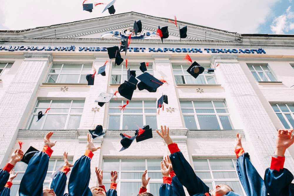graduation caps thrown in front of a school 